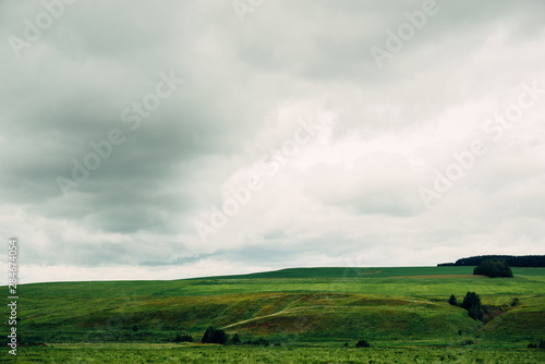 bad weather in summer day, dark dramatic rainy sky clouds over agricultural rural landscape, horizontal stock photo image