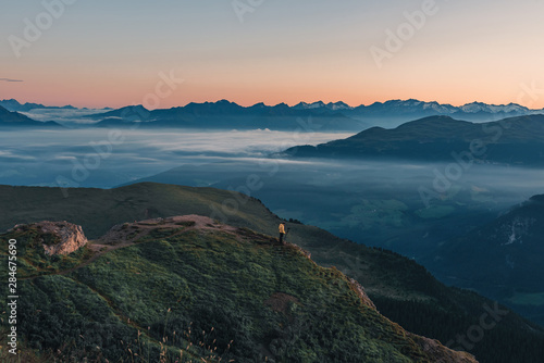 Nature photographer in action. Man standing on the mountain above a misty clouds waiting for sunrise