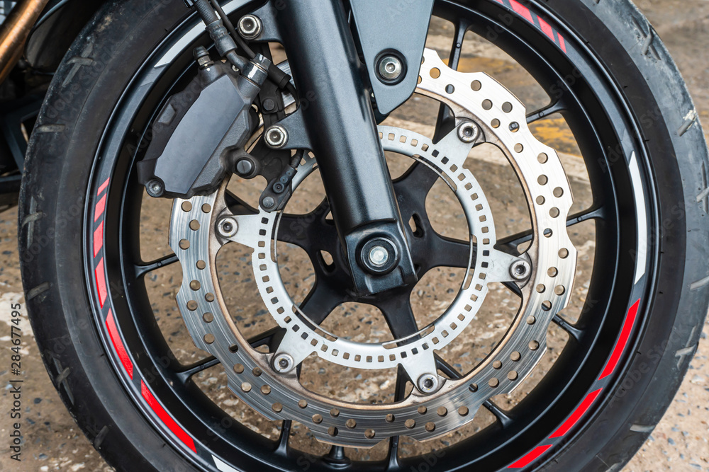 Front wheel close up of brakes system in a modern motorcycle modern with disc brakes.