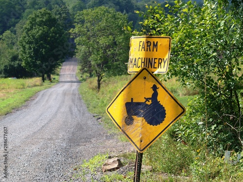 Traffic sign warns of Farm Machinery on a picturesque country road