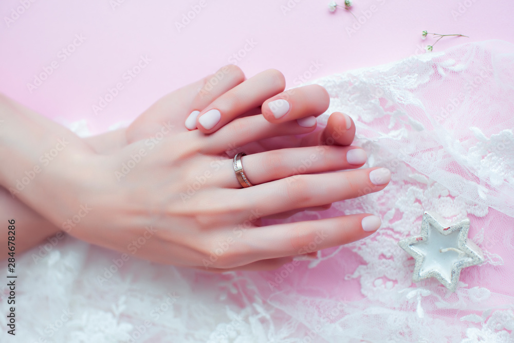 Fototapeta premium woman hands with manicure and wedding ring among white lace