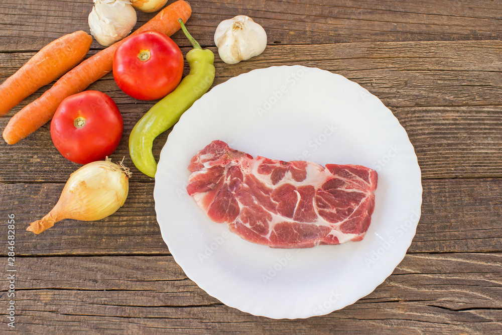 Raw pork meat chop with vegetable on wooden table Raw pork meat chop with vegetable on wooden table