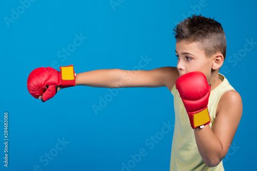 boy in red karate gloves performs a punch, concept