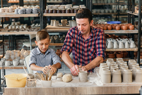 Cute middle age man with his little son having fun in the pottery.