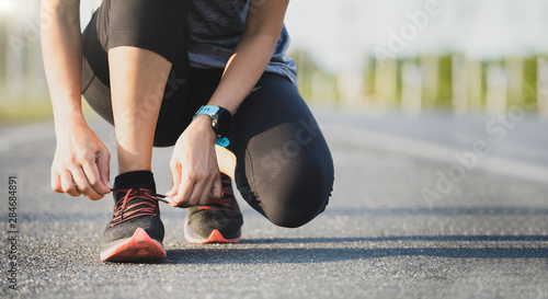 Running shoes runner woman tying laces for autumn run in forest park. Runner trying running shoes getting ready for run. Jogging girl exercise motivation heatlh and fitness. photo