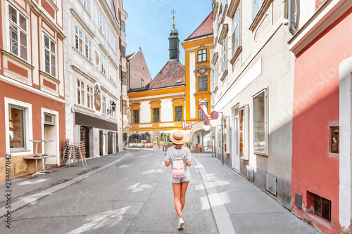 young asian woman with backpack and hat walking on city street in Europe