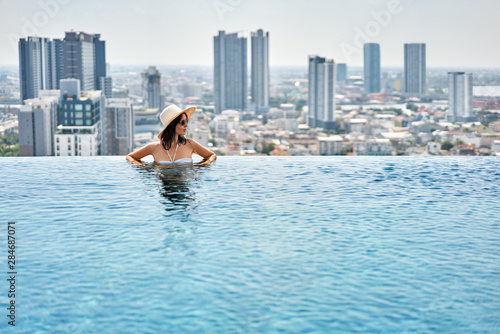 Photography Young woman enjoy summer vacation in roof top swimming pool