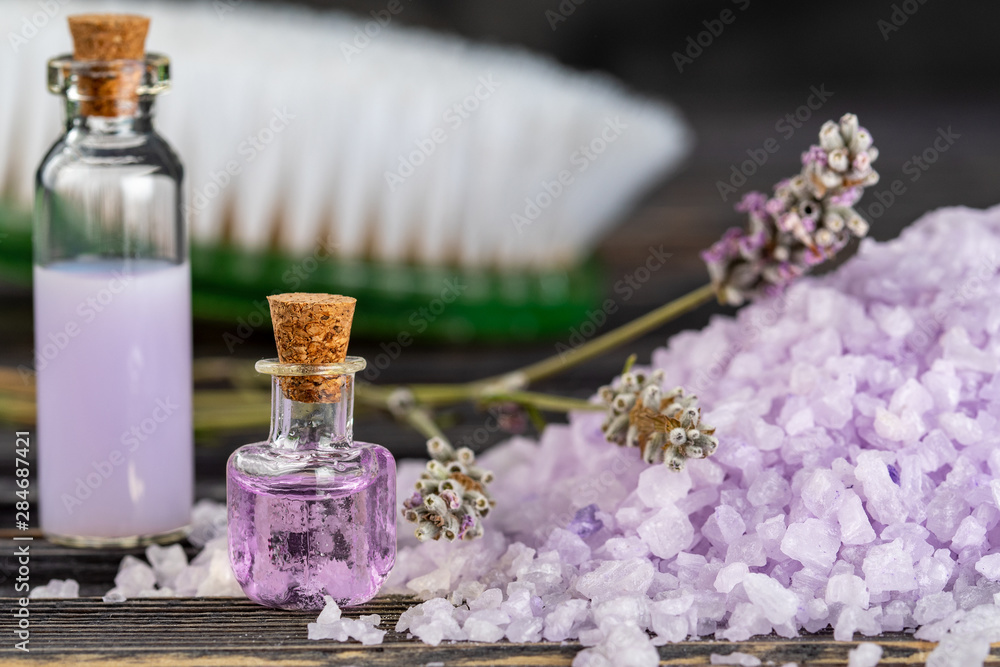 Lavender spa setting: salt, essential oil and dried flowers natural spa products and decor for bath on dark background.