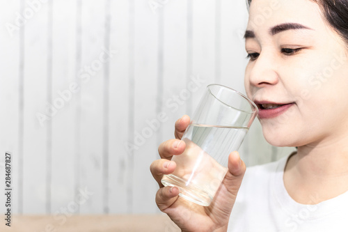 Cute asian young woman drink water from glass. Beautiful young girl hand holding drinking water.