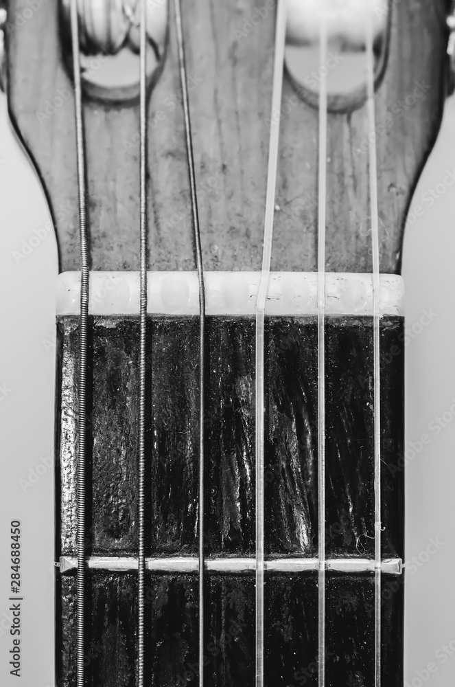 Nut, strings and frets between the headstock and the neck of a acoustic  guitar. Old guitar, worn out and dusty, black and white photo. Stock Photo  | Adobe Stock