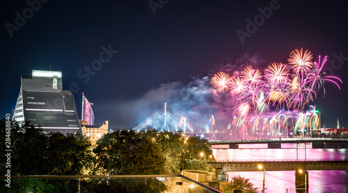  Panoramic view of Riga city with colorful fireworks glowing in the air. Picturesque scene of National library of Latvia, river Daugava and old town.   © Viesturs
