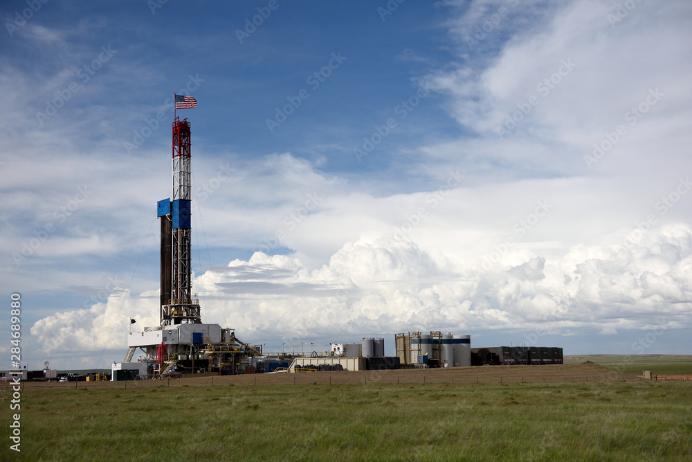 Crude oil exploration well site and drilling rig, with clouds and sky in the oil-rich Powder River Basin, Wyoming