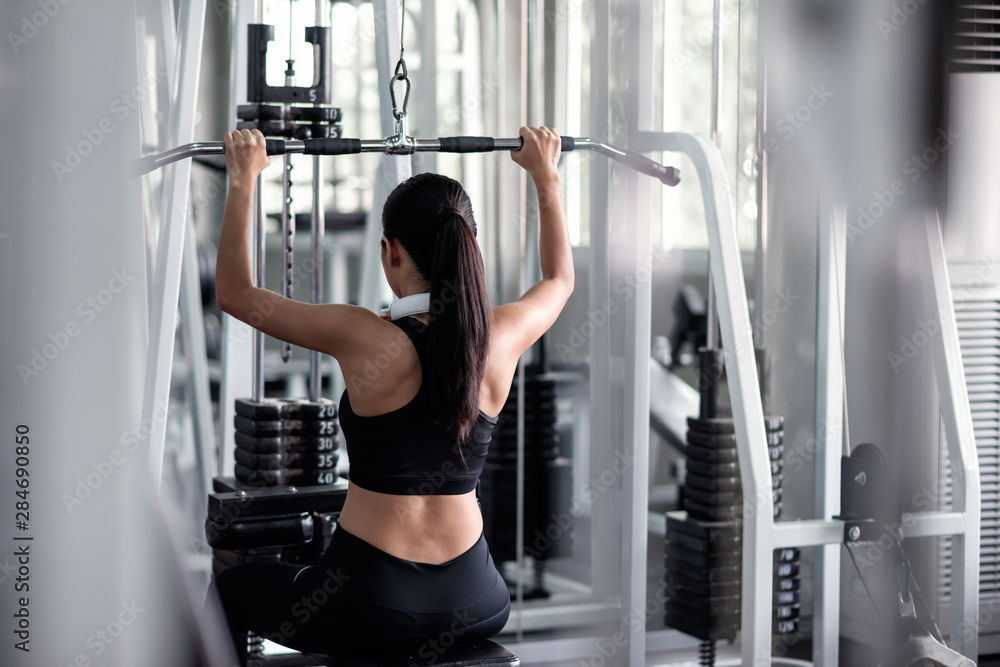 woman exercise with lat pulldown machine in gym woman exercise with lat pulldown machine in gym