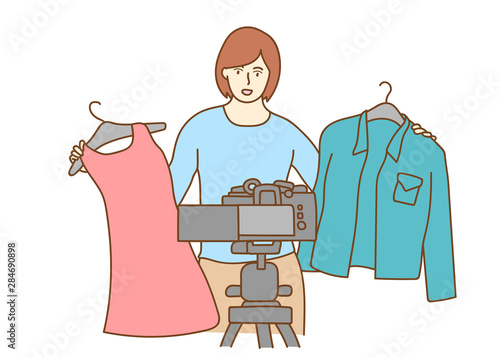 Camera recording a young female blogger choosing clothes while making a video