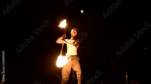 Fire show. Man juggles with two burning torches. Night show. Mastery of the fakir. Low angle photo