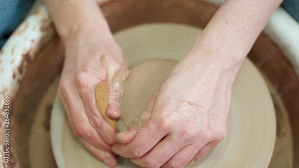 Close-up of female handwork with clay in a pottery studio. Close-up of female handwork with clay in a pottery studio.