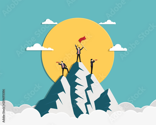 Team businessman holding a red flag and gold trophy stand on top of mountain