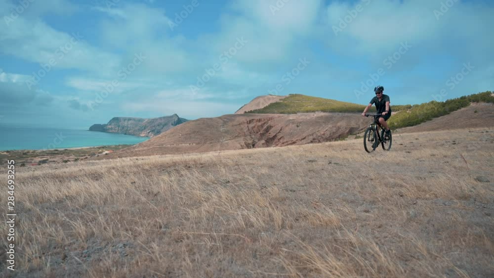 Man rides mountain bike near coast line and enjoys the beautiful scenic view Man rides mountain bike near coast line and enjoys the beautiful scenic view
