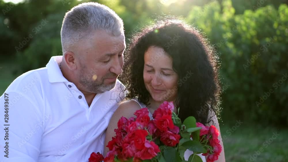 mature couple on a picnic date in the garder in the evening mature couple on a picnic date in the garder in the evening