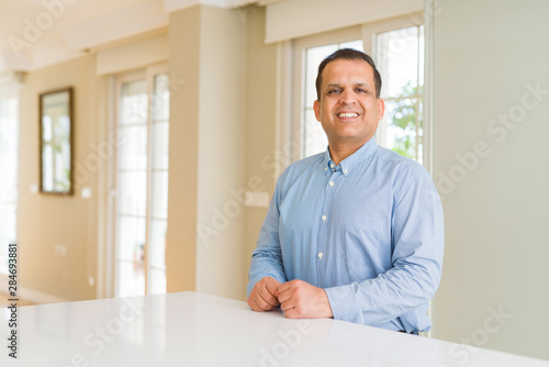 Middle age man sitting at home with a happy and cool smile on face. Lucky person. © Krakenimages.com