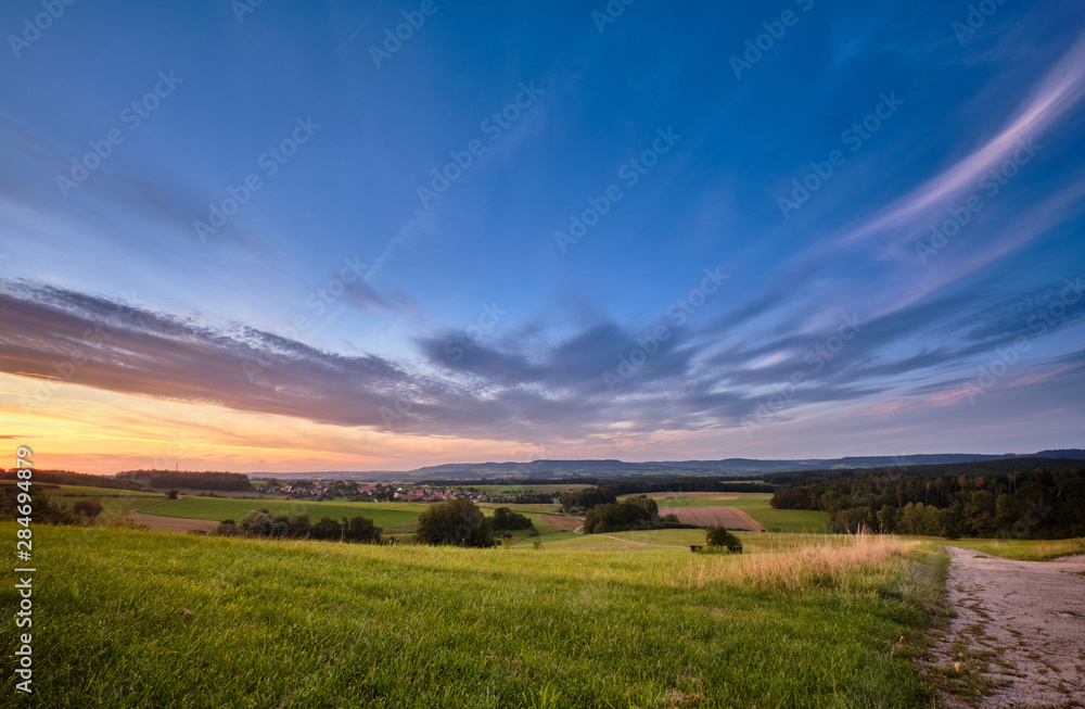 Beautiful summer sunset landscape with clouds in blue sky in the countryside with the view from Tauchersreuth to Beerbach in Franconia, Germany