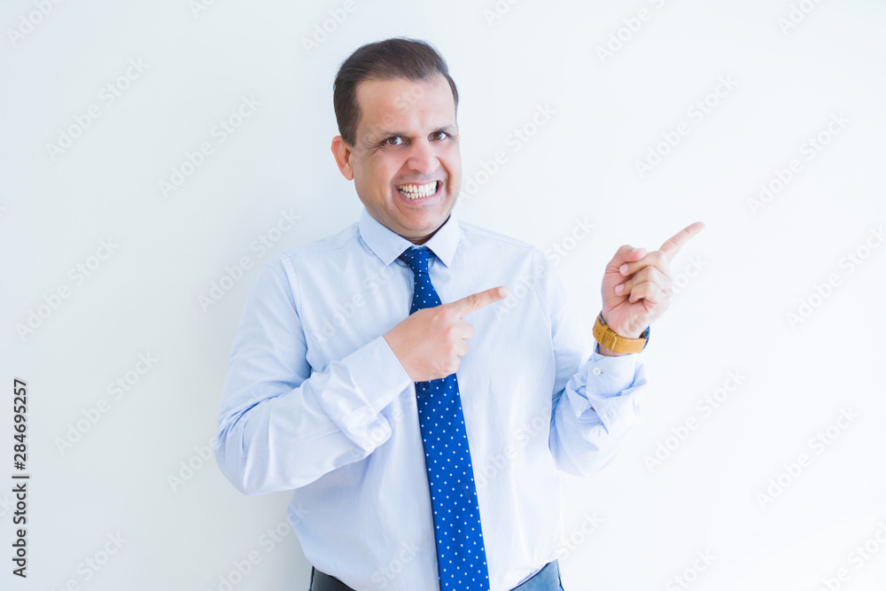 Middle age business man smiling and pointing to the side over white background Middle age business man smiling and pointing to the side over white background