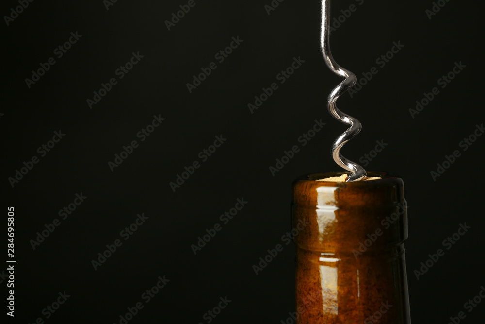 Bottle of wine and corkscrew on dark background, space for text Bottle of wine and corkscrew on dark background, space for text