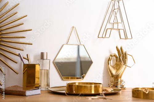 Composition with gold accessories on dressing table near white wall photo