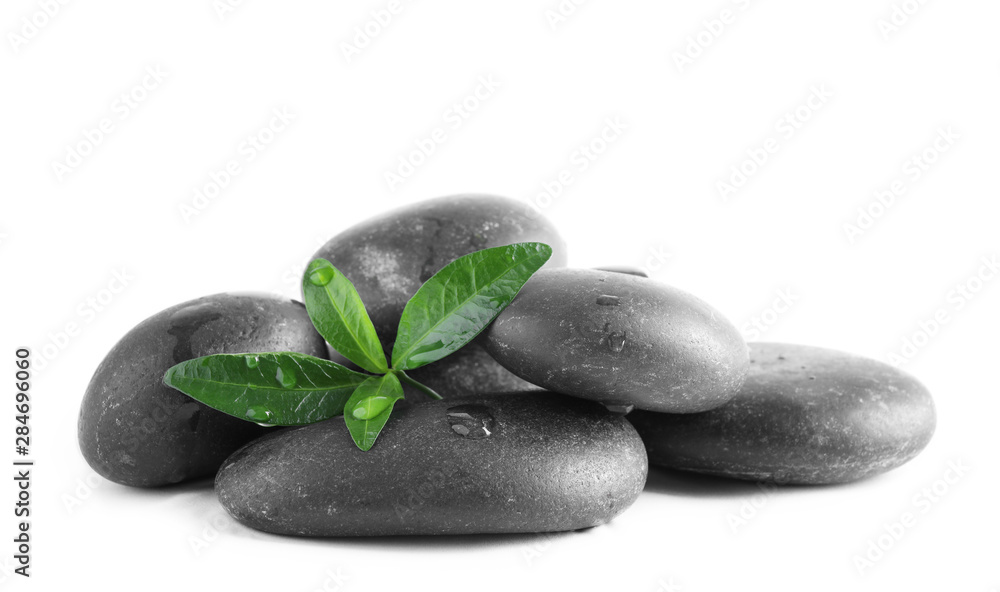 Spa stones and green leaves with water drops on white background Spa stones and green leaves with water drops on white background