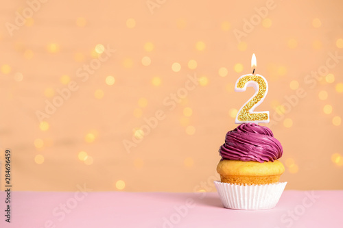 Canvas Print Birthday cupcake with number two candle on table against festive lights, space f