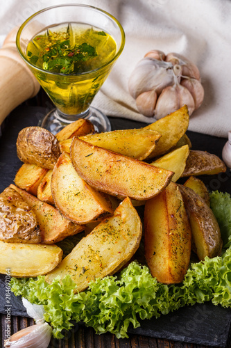 Potato wedges baked in their skins with lettuce on wooden background. photo