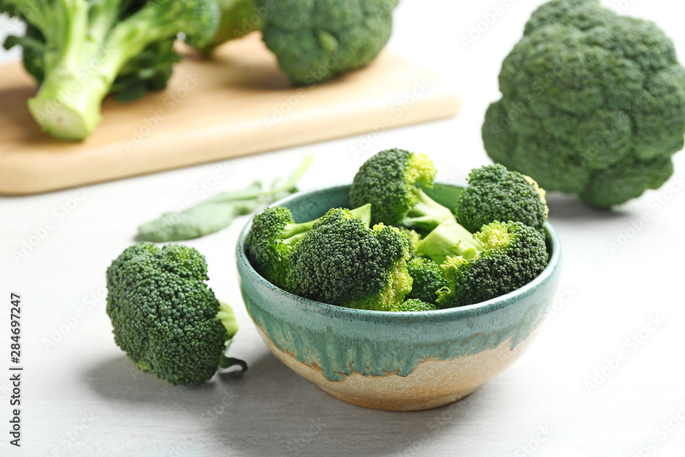 Bowl and fresh broccoli on light grey table Bowl and fresh broccoli on light grey table