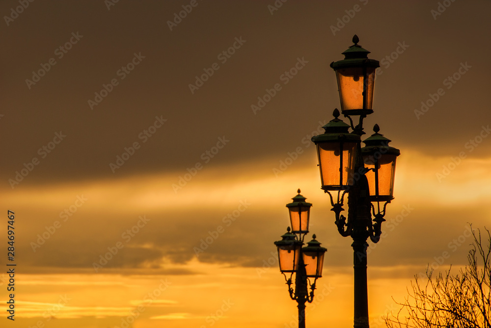 Old traditional Venice street lamps with golden sunset in a romantic and unique atmosphere (with copy space)