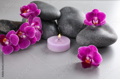 Spa stones  orchid flowers and candle on grey table