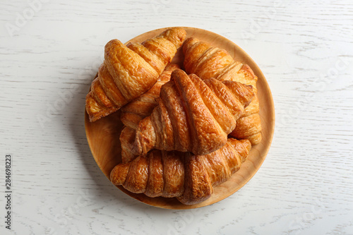 Plate with tasty croissants on white wooden background, top view. French pastry