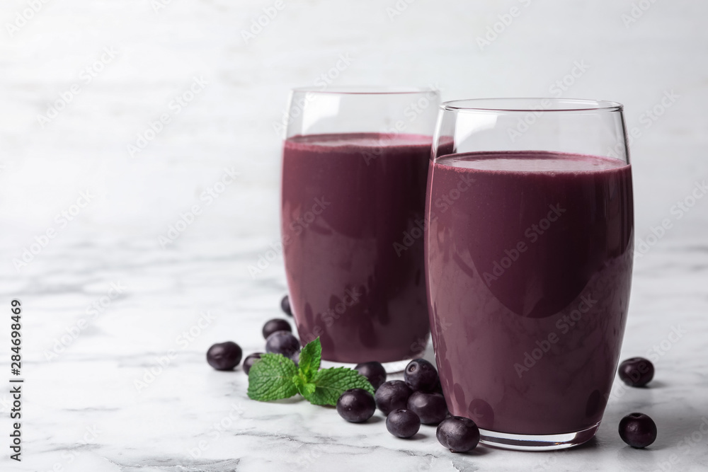 Tasty acai drink in glasses and berries on marble table Tasty acai drink in glasses and berries on marble table