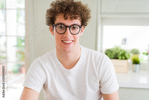 Young handsome man wearing glasses with a happy and cool smile on face. Lucky person.