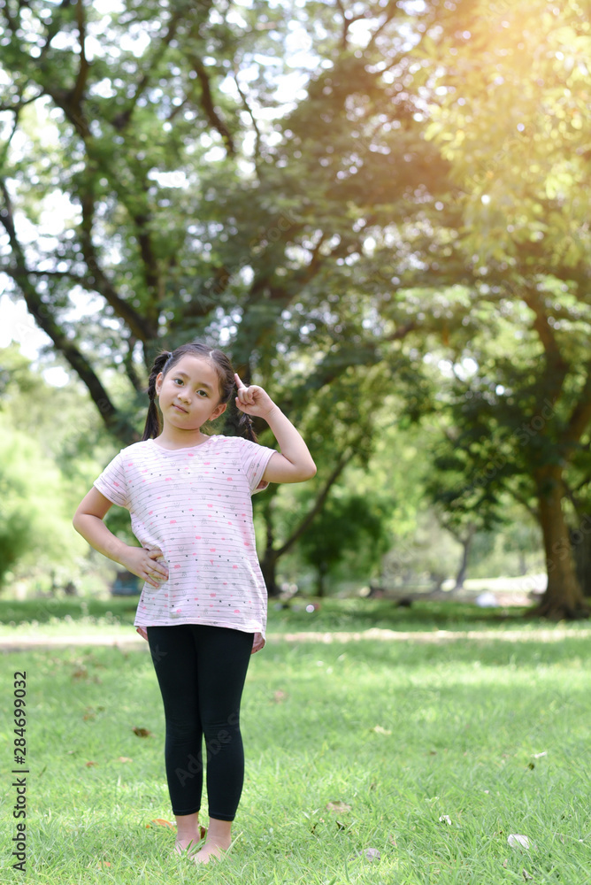 Little girl posting thinking action with green park background Little girl posting thinking action with green park background