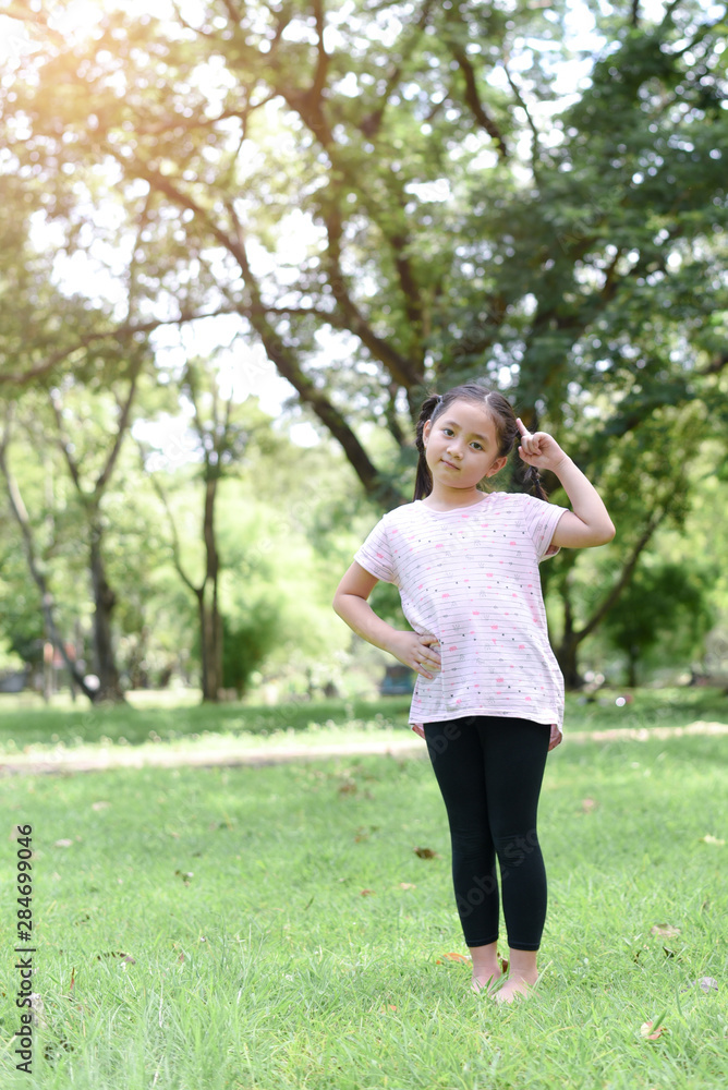 Little girl posting thinking action with green park background Little girl posting thinking action with green park background
