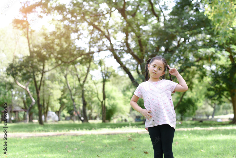 Little girl posting thinking action with green park background Little girl posting thinking action with green park background