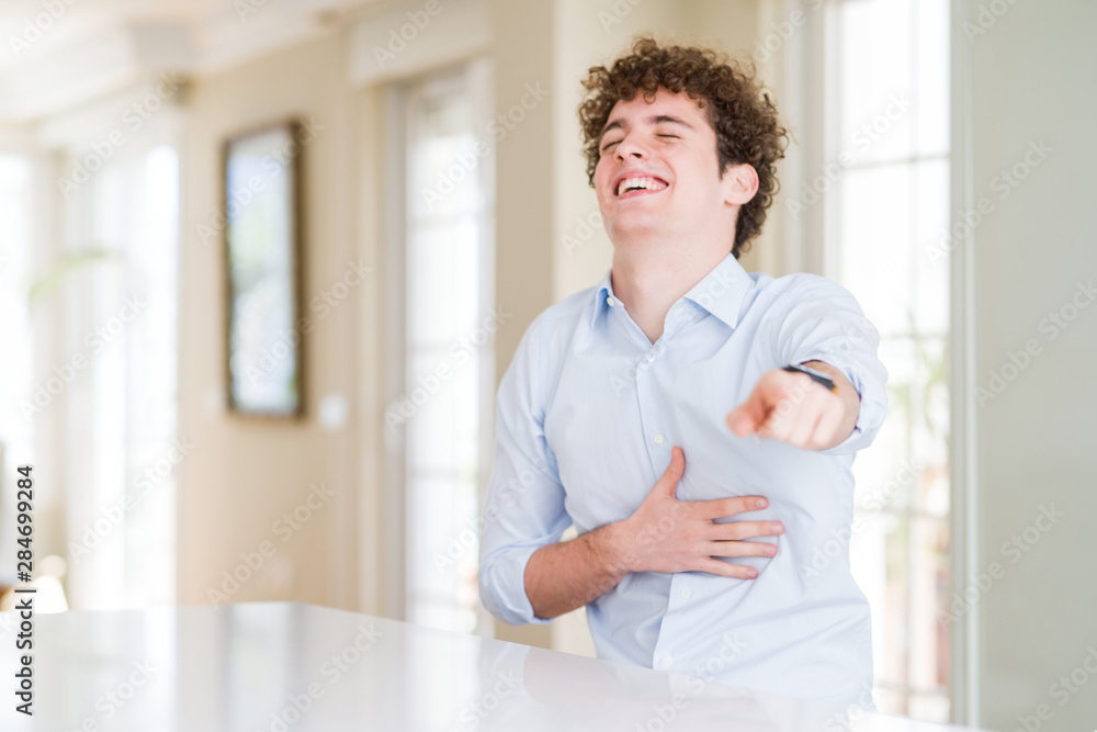 Young business man with curly read head laughing at you, pointing finger to the camera with hand over body, shame expression Young business man with curly read head laughing at you, pointing finger to the camera with hand over body, shame expression