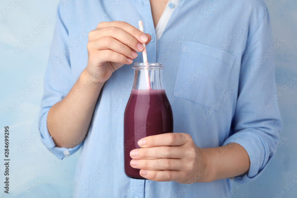 Woman with bottle of fresh acai drink and straw, closeup