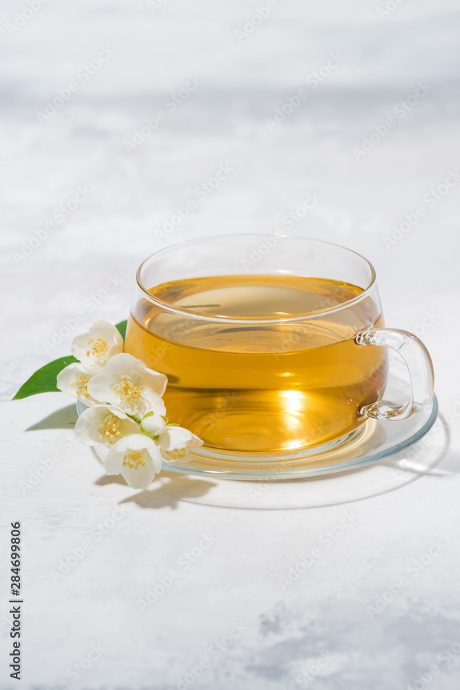 glass cup with green tea on a white background and jasmine, vertical glass cup with green tea on a white background and jasmine, vertical