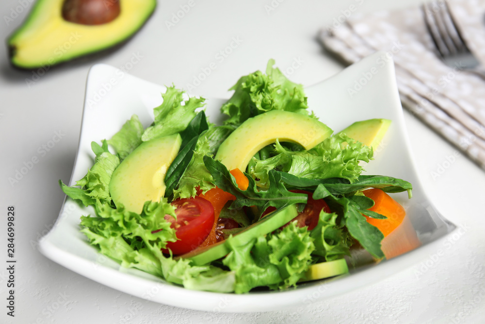 Delicious avocado salad in bowl on white table
