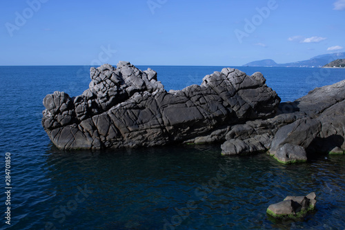 Amazing sunset seascape with rock and sea pebbles, vertical travel background, popular tourist location photo