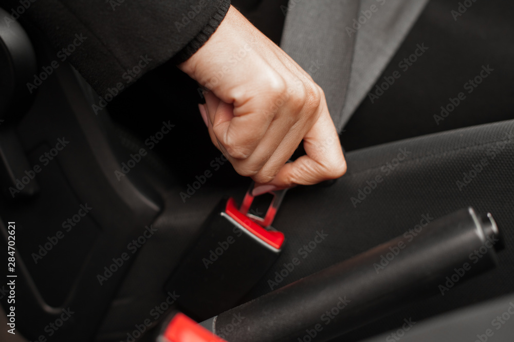 Female hand fastens the seat belt of the car.