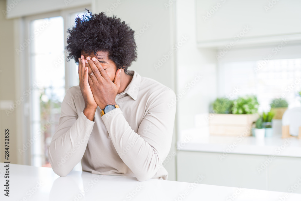 African American man at home with sad expression covering face with hands while crying. Depression concept. African American man at home with sad expression covering face with hands while crying. Depression concept.