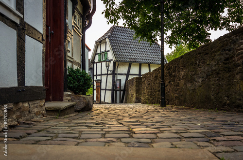 Fototapeta Naklejka Na Ścianę i Meble -  Old cobblestone alley, half-timbered houses on the left and a stone wall right on the edge of the picture, Hattingen, Germany