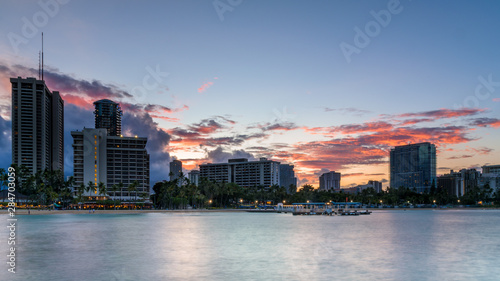 View of Waikiki beach skyline  at dawn on a summer s day. The sky is red  as the sun rises behind the buildings