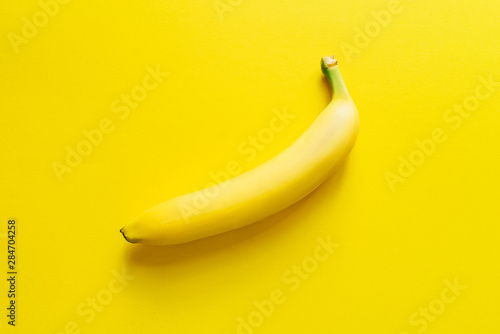 One ripe banana on a yellow background. Flat lay.